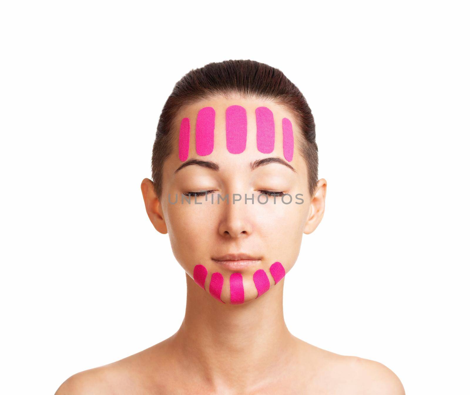 Beautiful brunette woman with vertical kinesiology facelift tapes on her forehead and chin, front view.