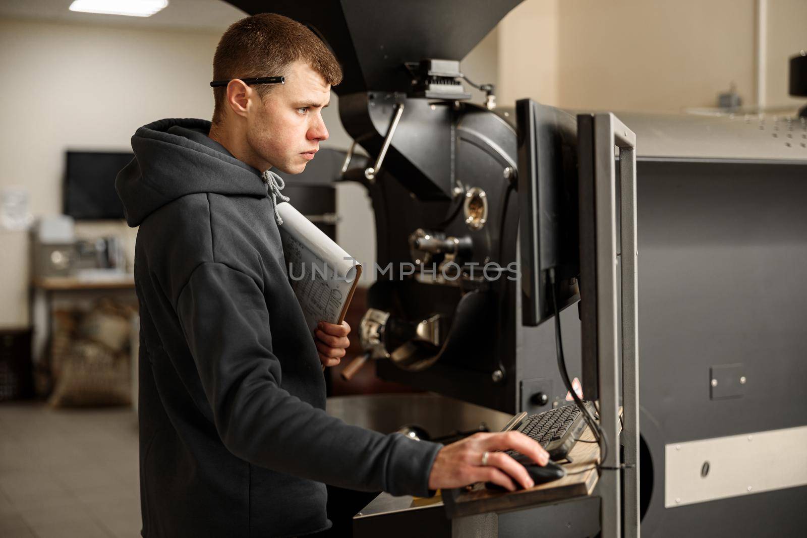 Young specialist worker is roasting coffee in hangar