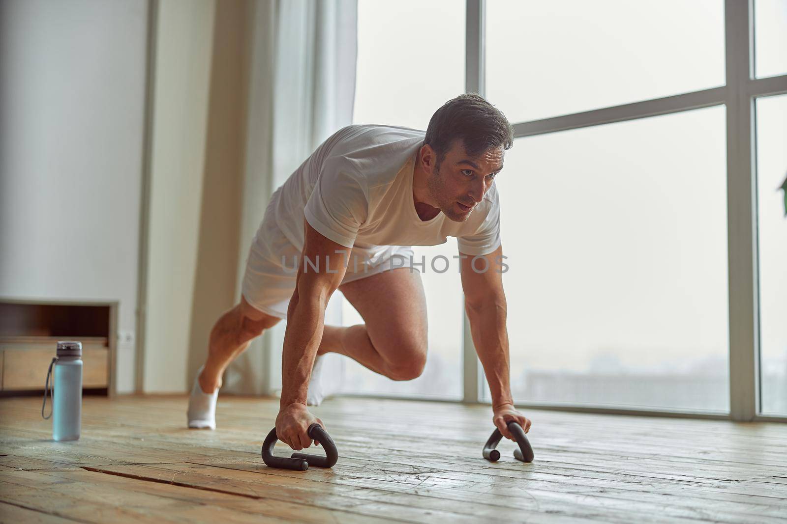 Man is spending active time at home during quarantine and doing core workout alone with equipment