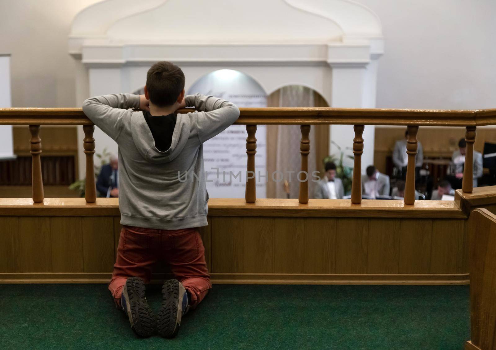 Rear view of a little boy kneeling and praying in a church