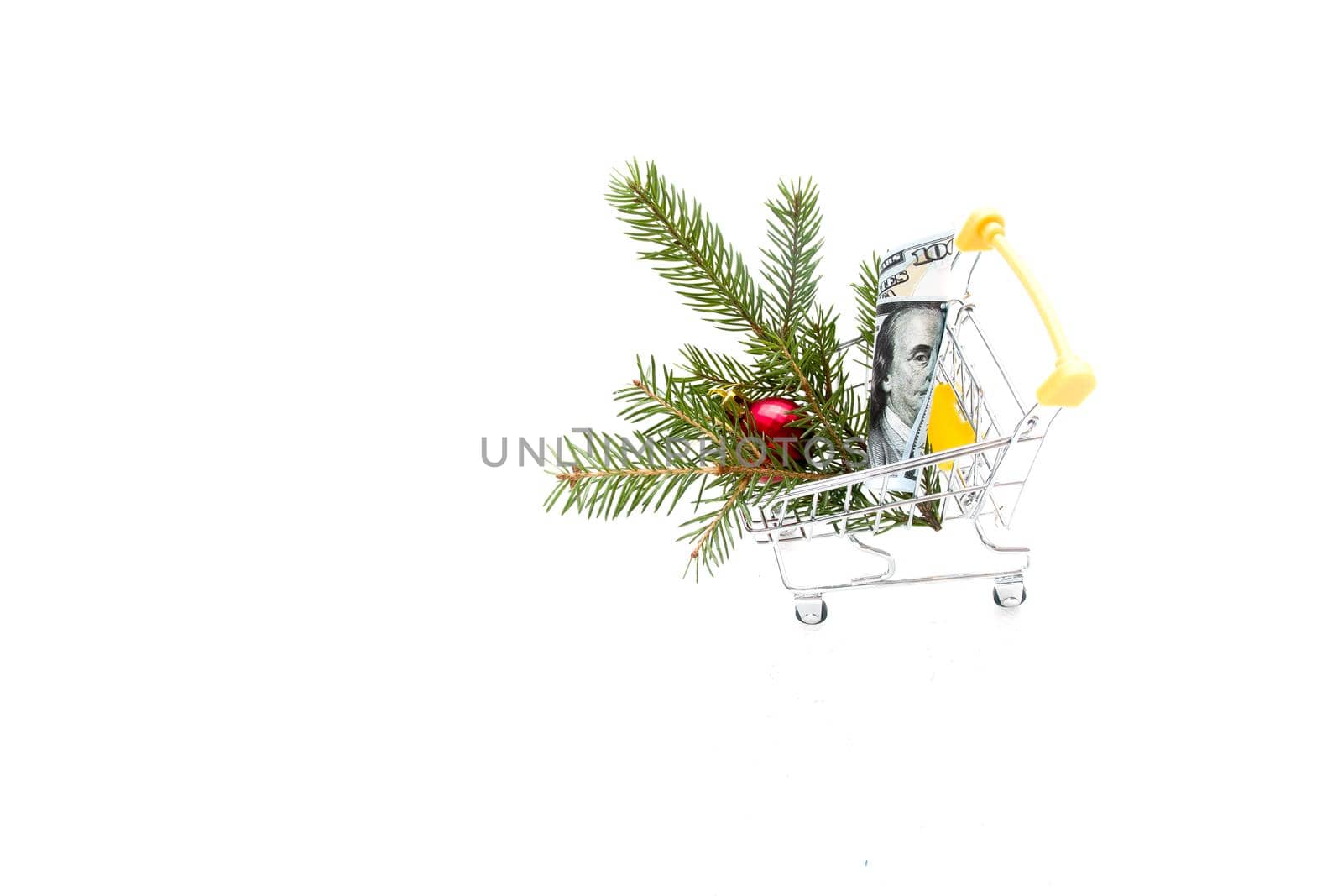concept of shopping before christmas, christmas decor and dollar bill in a shopping trolley on a white background place copy isolation