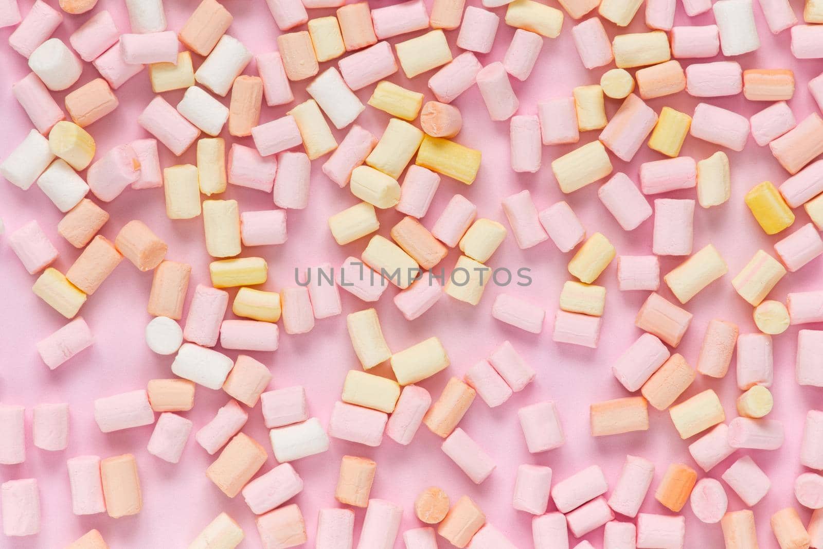 Top view on multi-colored marshmallows on a monochrome pink background by lunarts