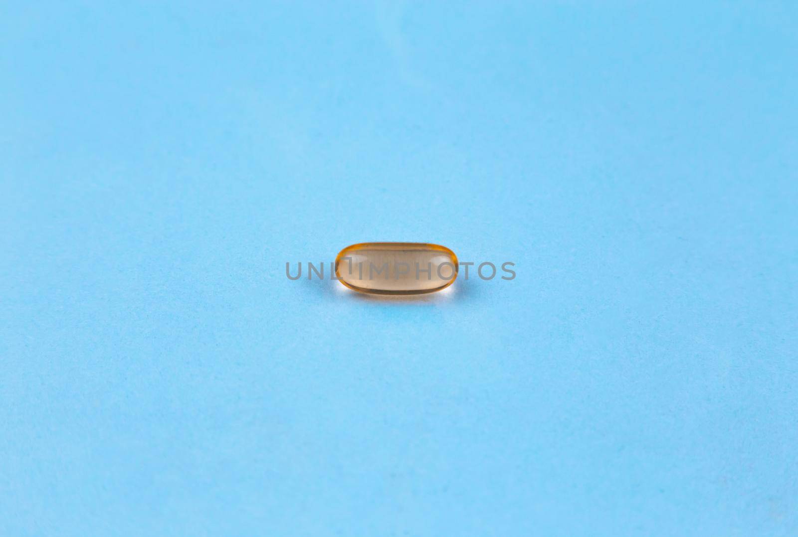 Fish oil supplement capsule isolated on blue background by lunarts