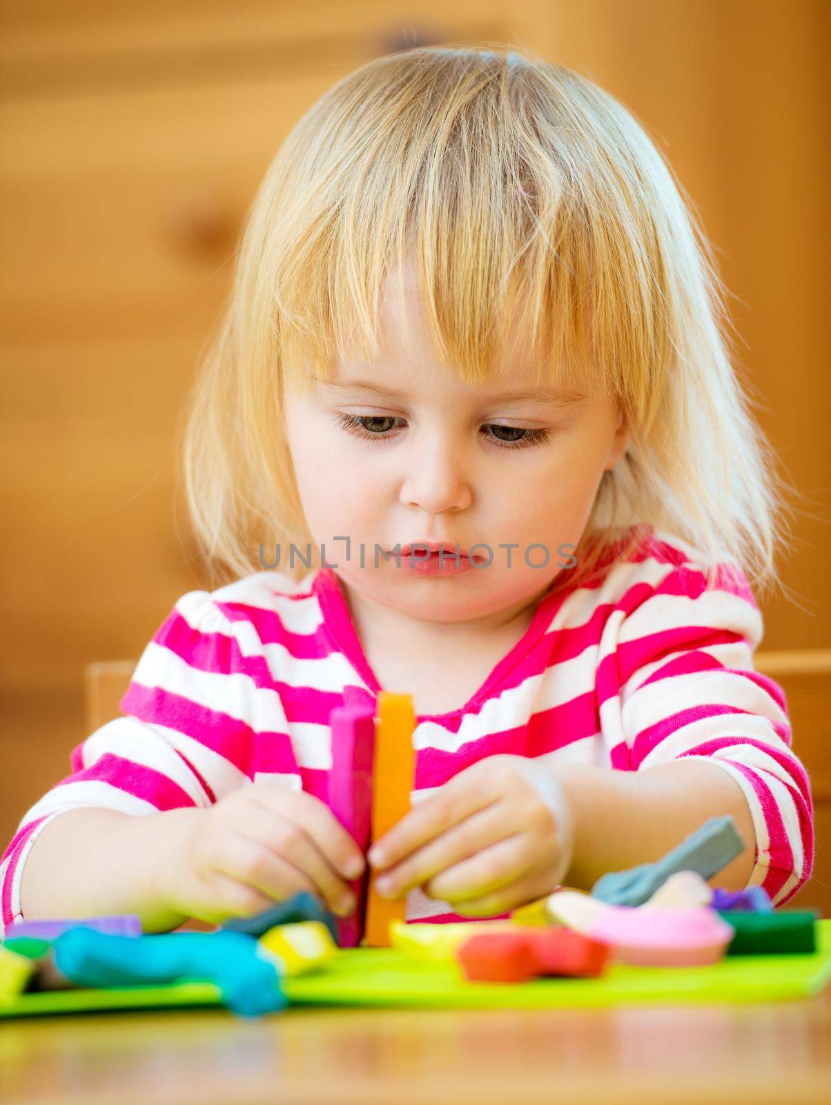Smiling girl playing with plasticine at home