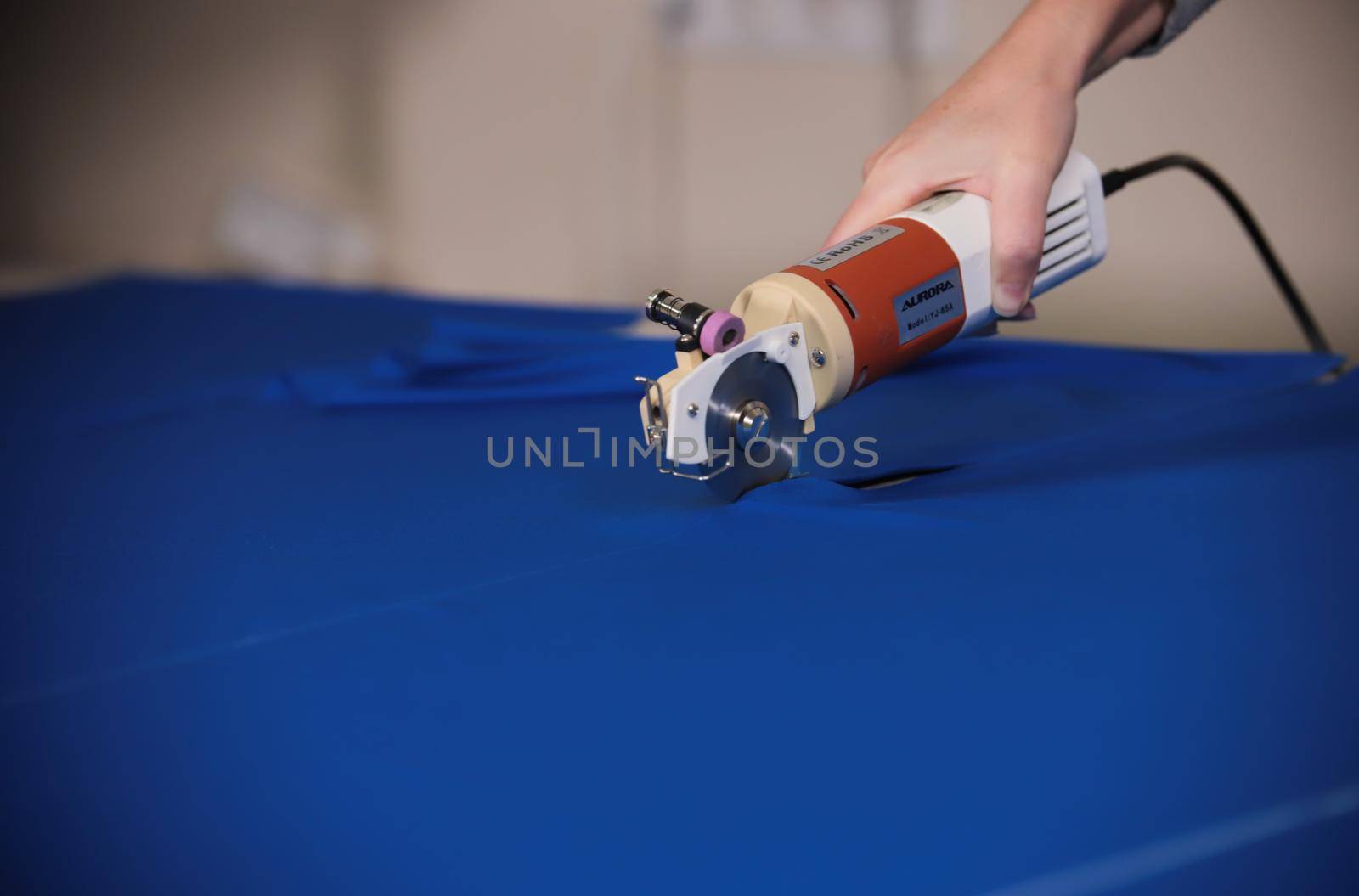 Worker at the factory sketching marks on the cloth. Cutting the cloth using the instrument. Clothing industry