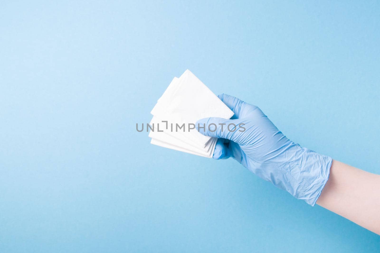 hand in blue disposable medical glove holds disposable paper napkins, nose hygiene, runny nose and common cold concept
