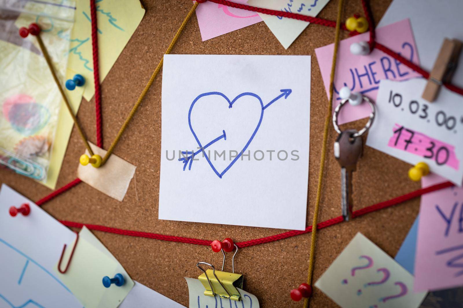 Love search concept. Close-up view of a detective board with evidence. In the center is a white sheet attached with a red pin with the heart icon by lunarts