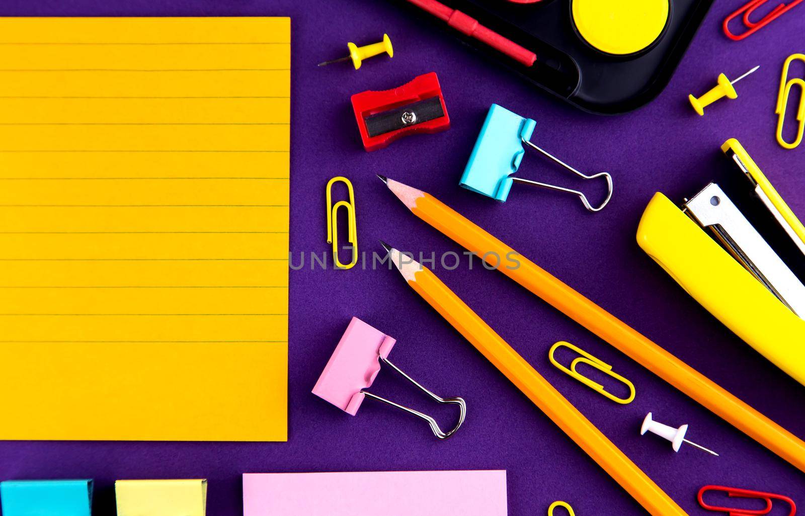 School office supplies stationery on a purple background desk with copy space. Back to school concept.