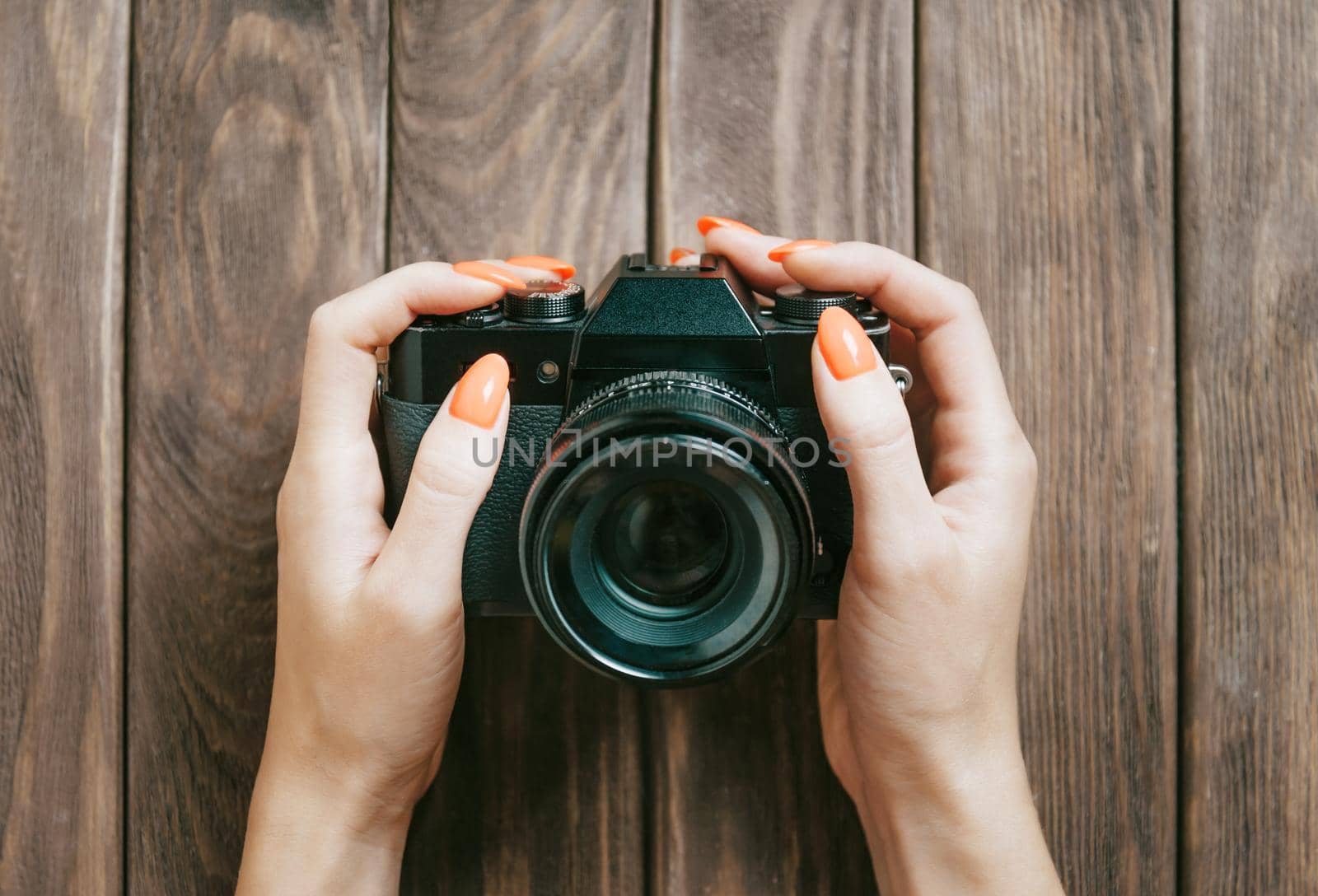 Woman holding photo camera at wooden table, pov. by alexAleksei