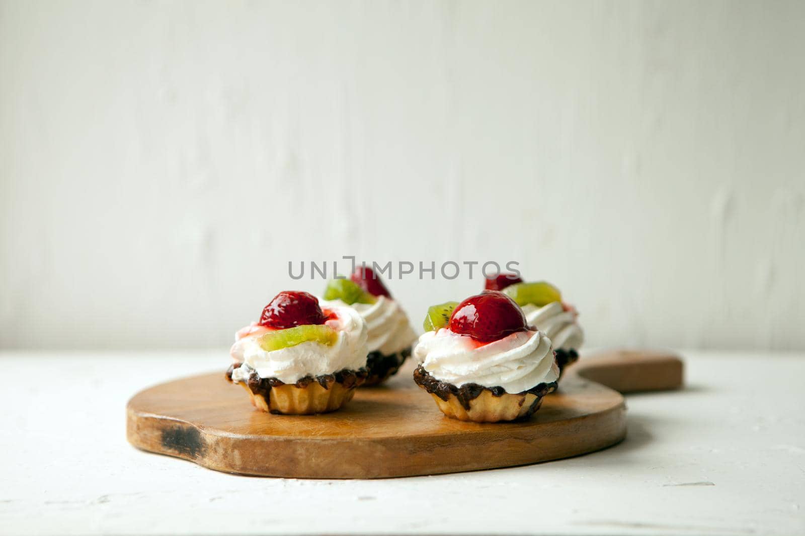 fresh cupcakes with cottage cheese on vintage tray-tasty muffin with strawberry and kiwi on wooden plate