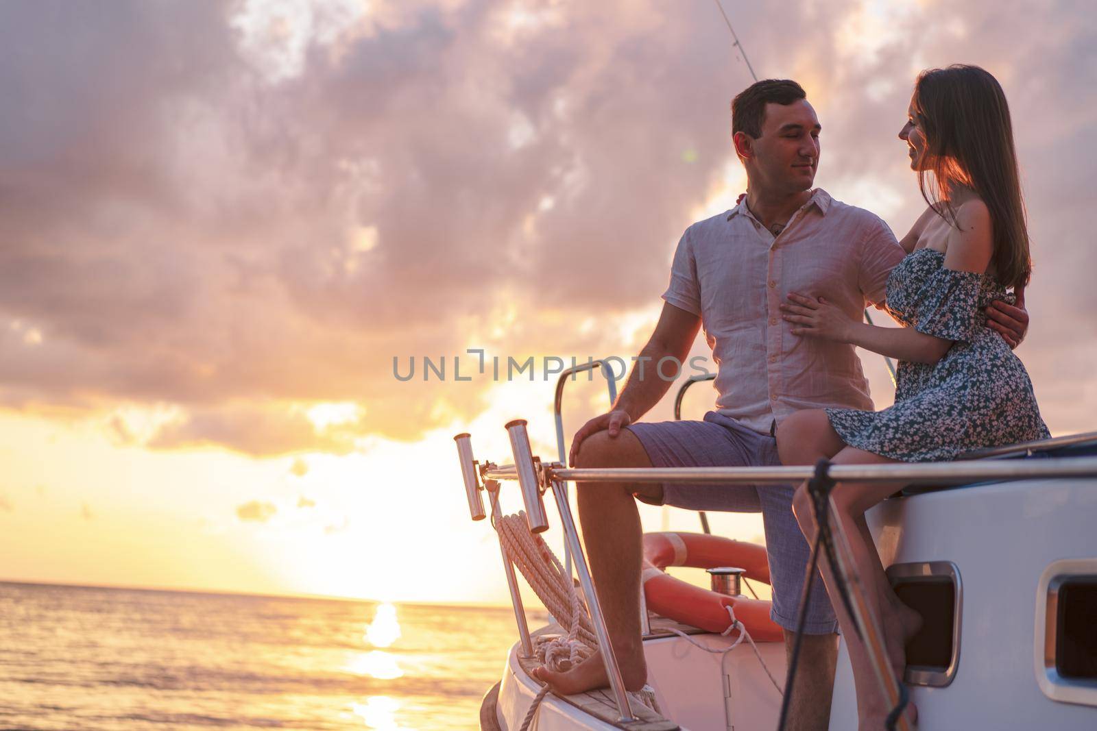 Beautiful couple looking at sunset from the yacht by Fabrikasimf