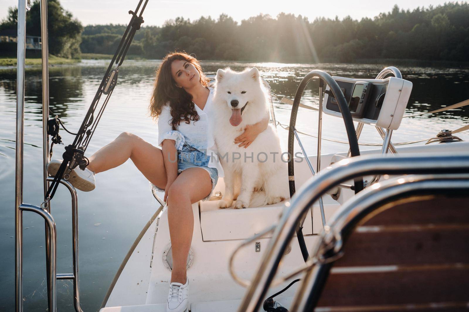 a happy woman with a big white dog on a white yacht in the sea.