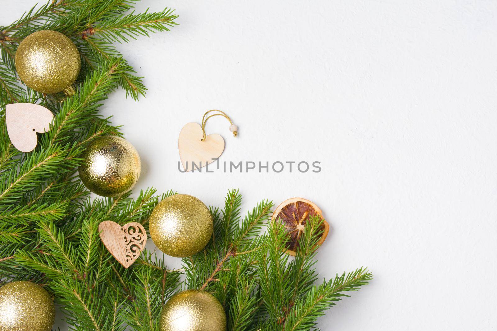 christmas tree golden balls and natural fir branches on a white background top view copy place, wooden eco friendly Christmas tree toys on fresh spruce branches by natashko