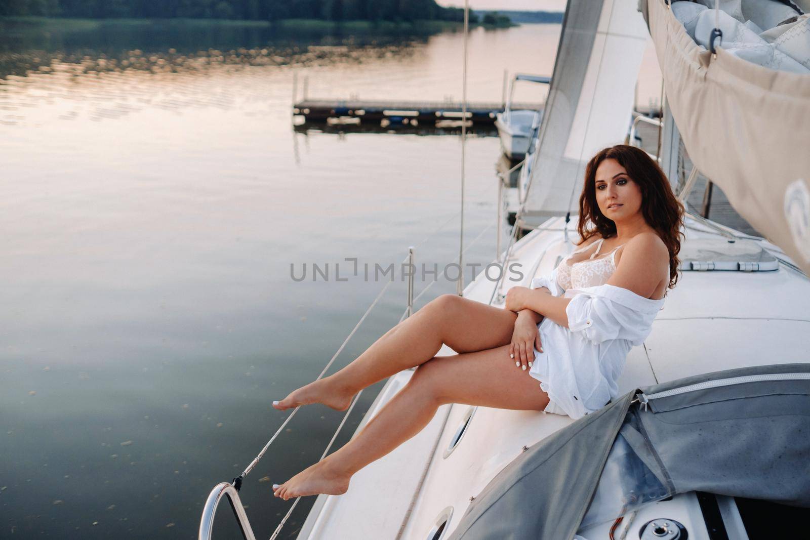 sexy woman in a white shirt enjoys the sunset on her private white yacht by Lobachad
