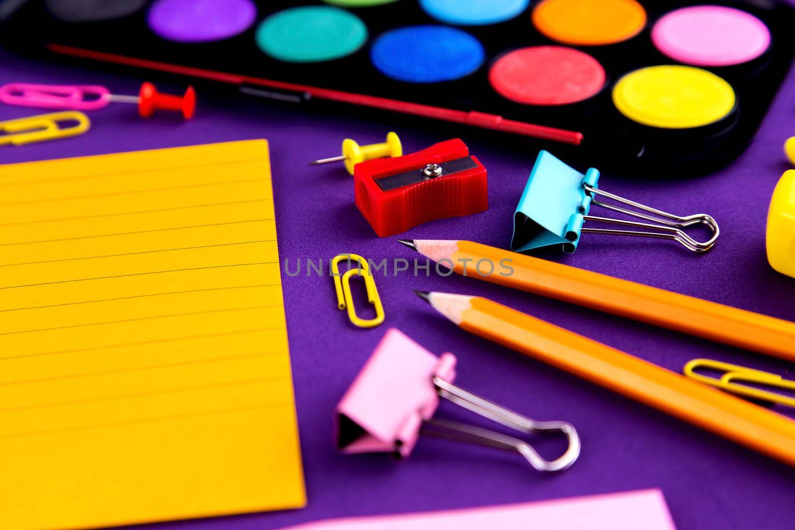 School office supplies stationery on a purple background desk with copy space. Back to school concept by lunarts