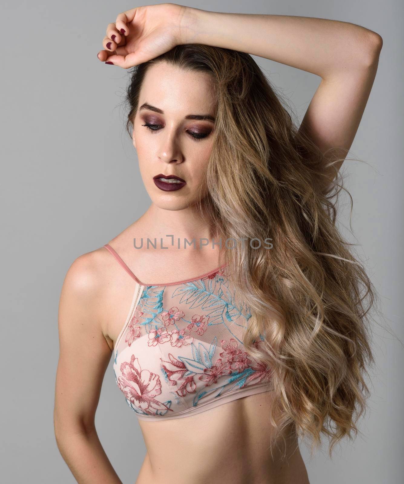 Beautiful caucasian woman with very long hair and blue eyes. Female wearing colored lingerie. Wavy hairstyle. Studio shot.