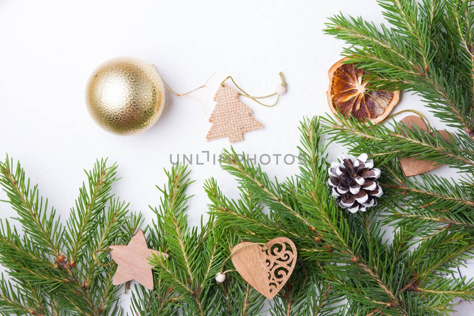 christmas tree golden balls and natural fir branches on a white background top view copy place, wooden eco friendly Christmas tree toys on fresh spruce branches by natashko
