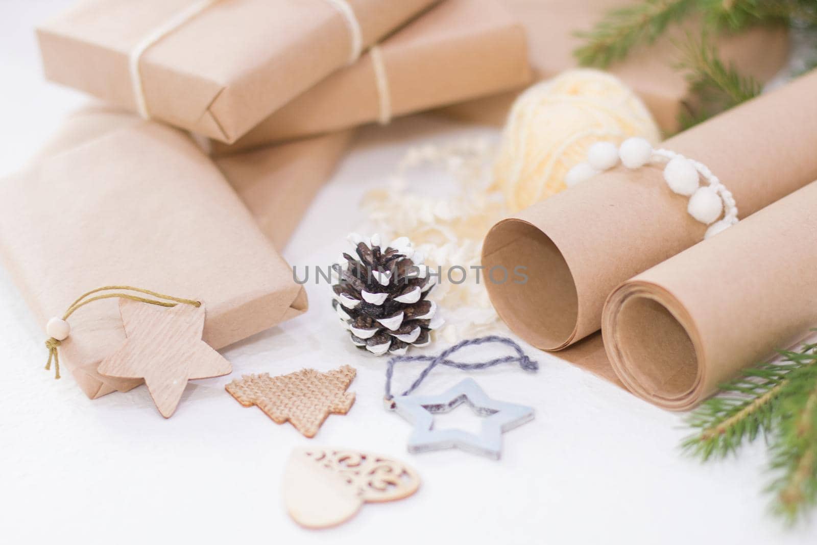 eco friendly gift box packaging for christmas or new year, wooden christmas toys, box wrapped in kraft paper with a spruce branch and a wooden star on a white background by natashko