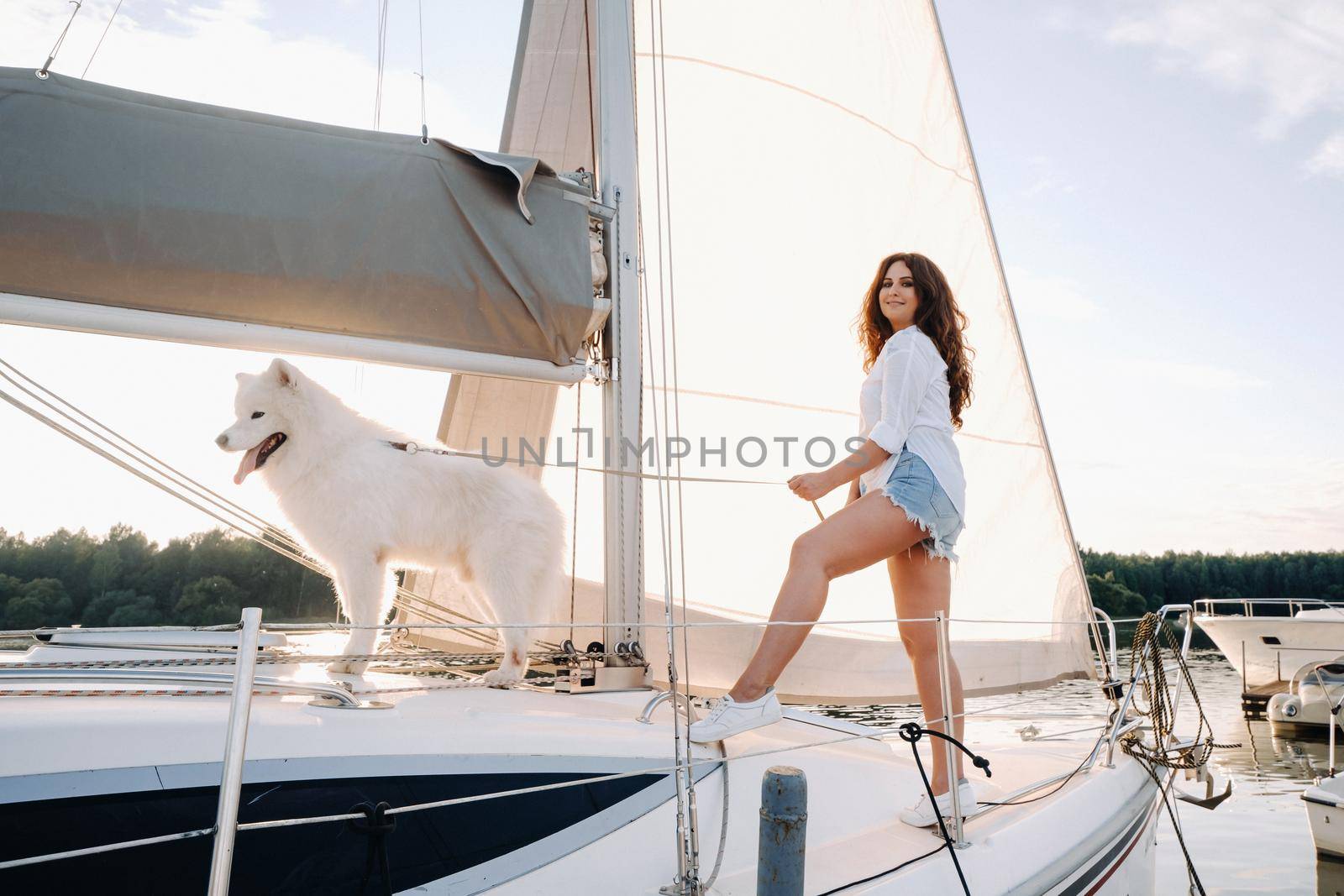 a happy woman with a big white dog on a white yacht in the sea by Lobachad
