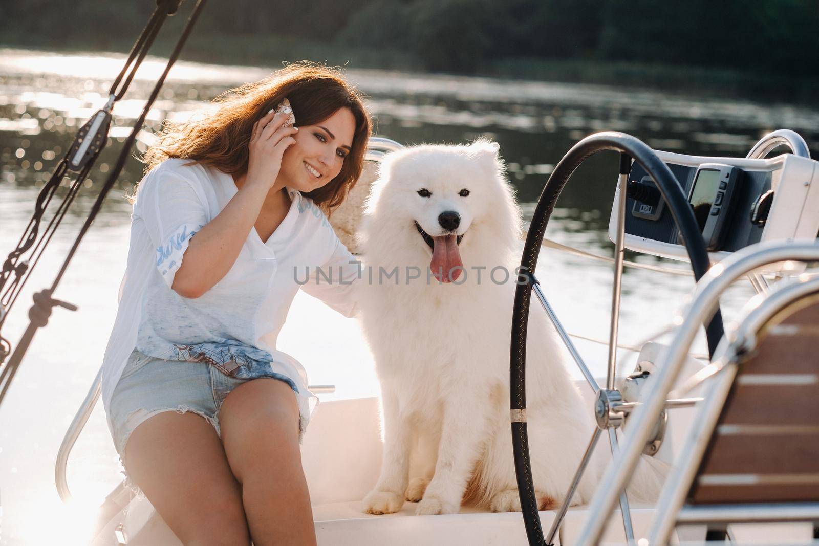 a happy woman with a big white dog on a white yacht in the sea.