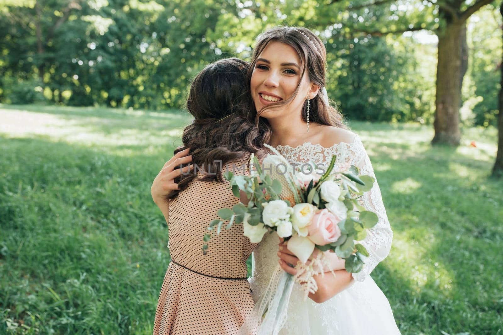 Beautiful bride in a wedding dress in the forest is hugging a girl by lunarts