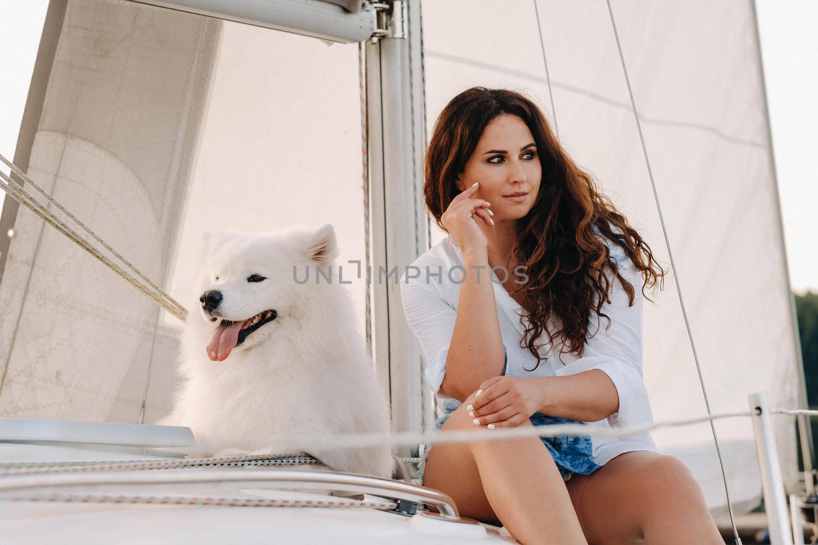 a happy woman with a big white dog on a white yacht in the sea.