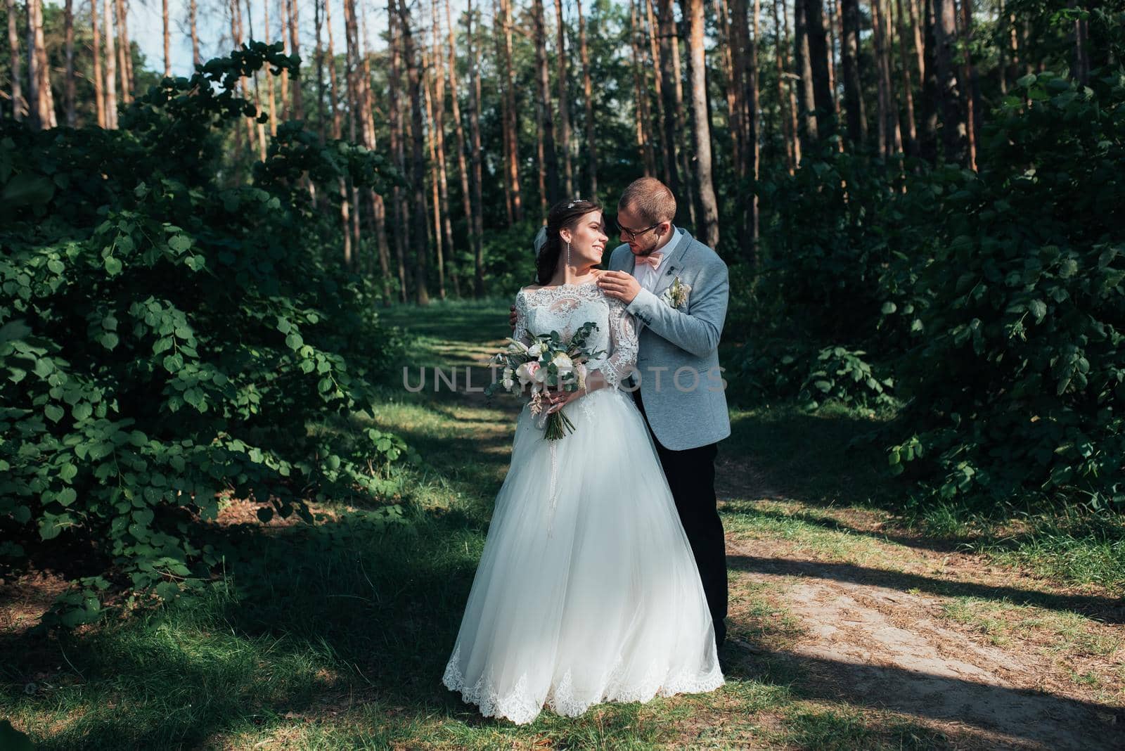 Wedding photo of the bride and groom in a gray-pink color on nature in the forest and rocks