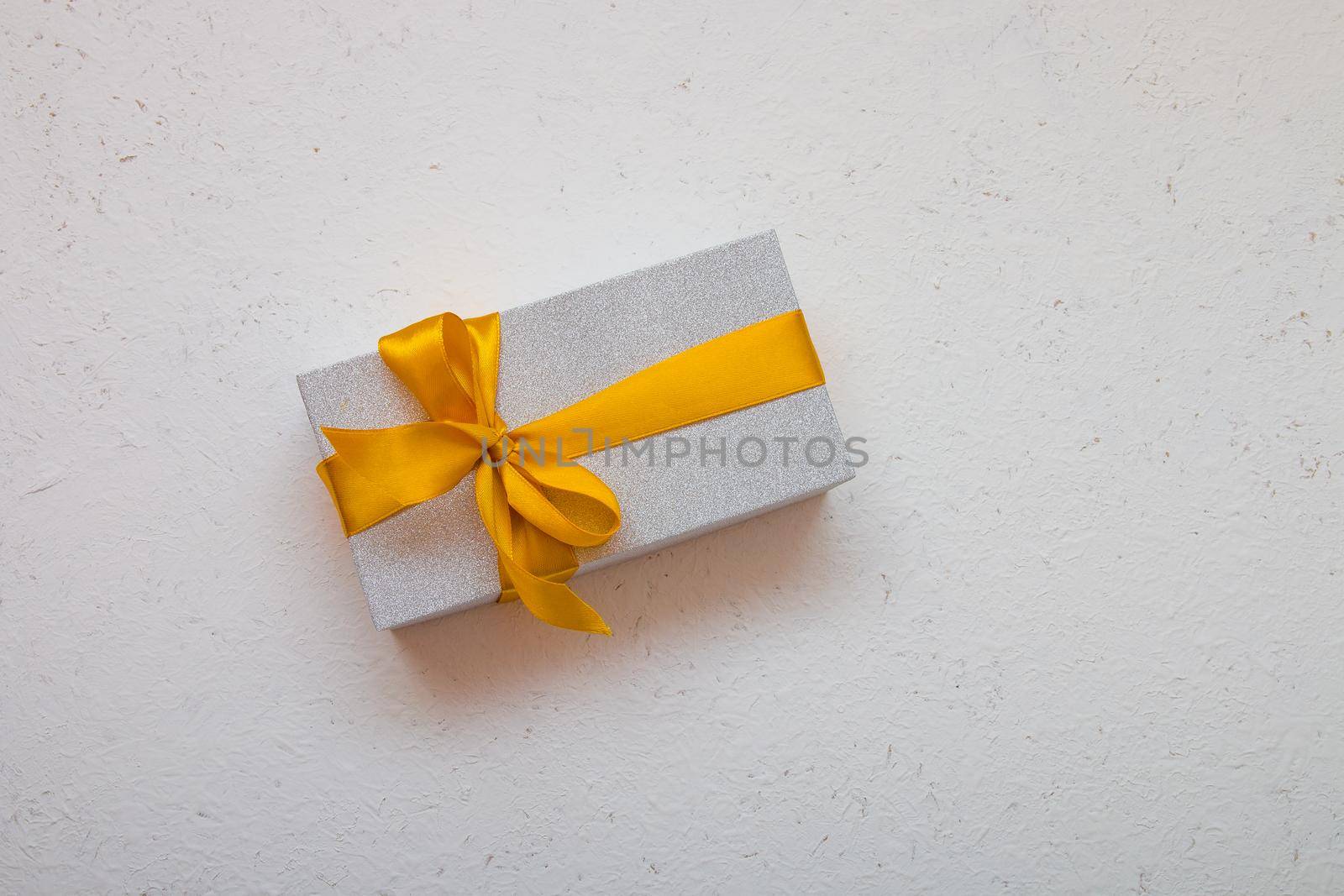 shiny gift box with a gold bow on a white background top view copy space