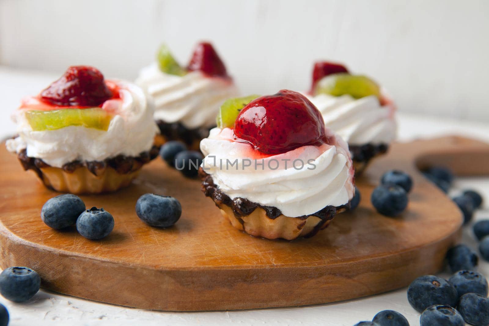 fresh cupcakes with cottage cheese on vintage tray-tasty muffin with strawberry and kiwi on wooden plate