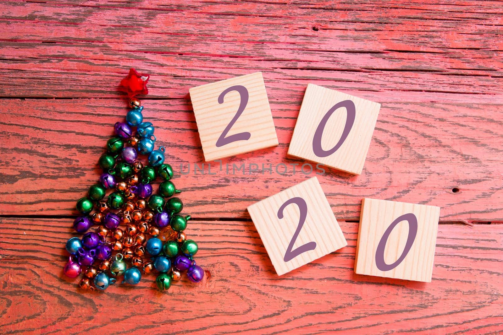 tree made of beads and shiny bells, wooden squares for your new year date, red wooden background 2020 text date