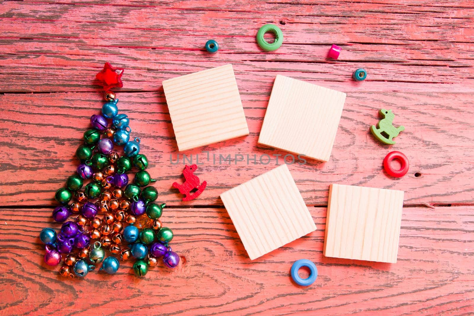 tree made of beads and shiny bells, wooden squares for your new year date, red wooden background