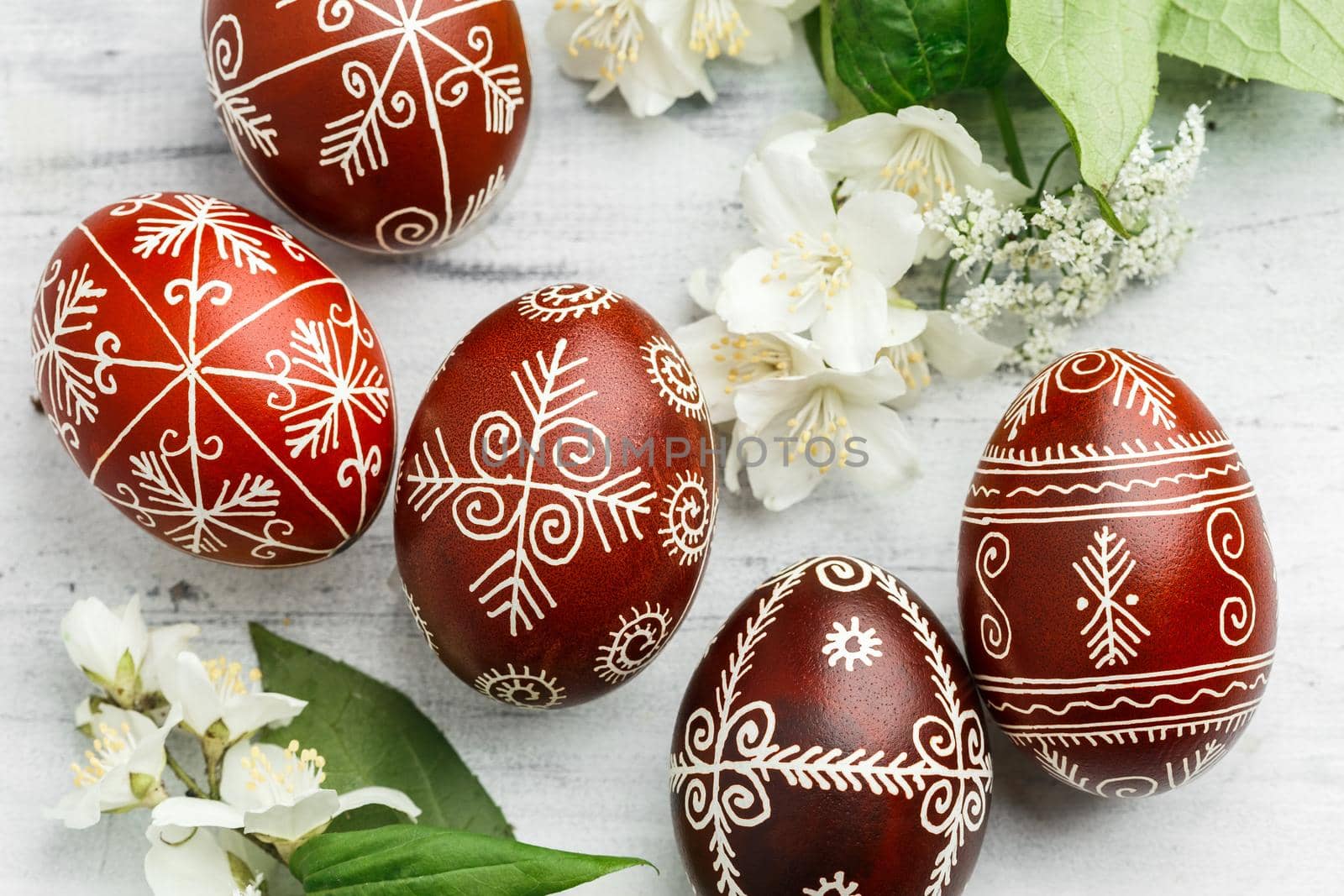 Red and black handmade Easter Pysanka eggs. Ukrainian pysanky decorated with wax-resist dyeing technique. White wooden background