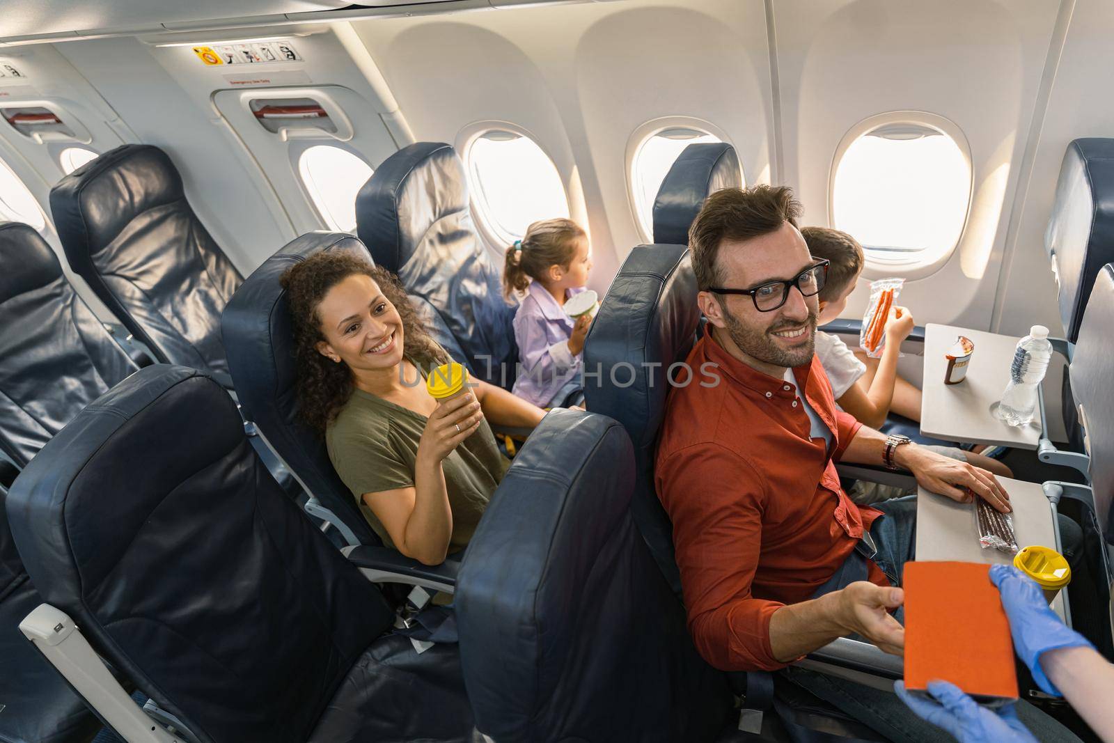 Top view of happy family enjoying the lunch while traveling together by plane. Trip and family concept