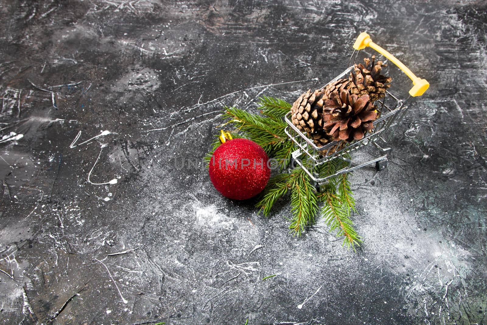 Christmas shopping, online shopping, shopping cart with pine cones and Christmas red ball, spruce branch, black background, copy space