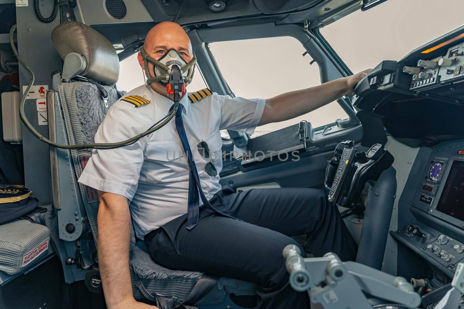 Professional pilot sitting at the controls in airplane and wearing an oxygen mask. Profession concept