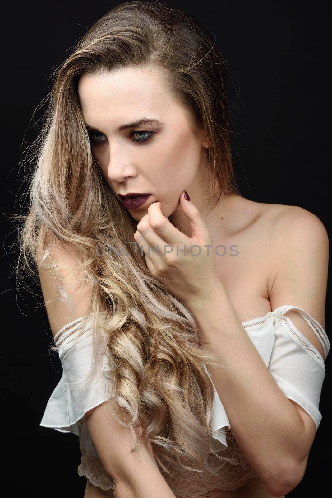 Young woman with long hair and blue eyes against black background with purple make-up. Fashion concept.