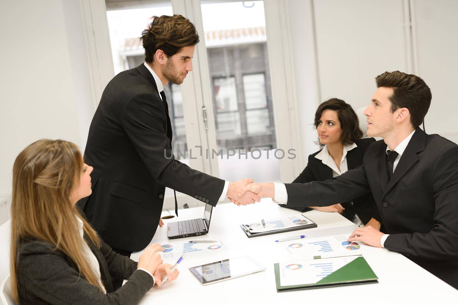 Four business people shaking hands, finishing up a meeting