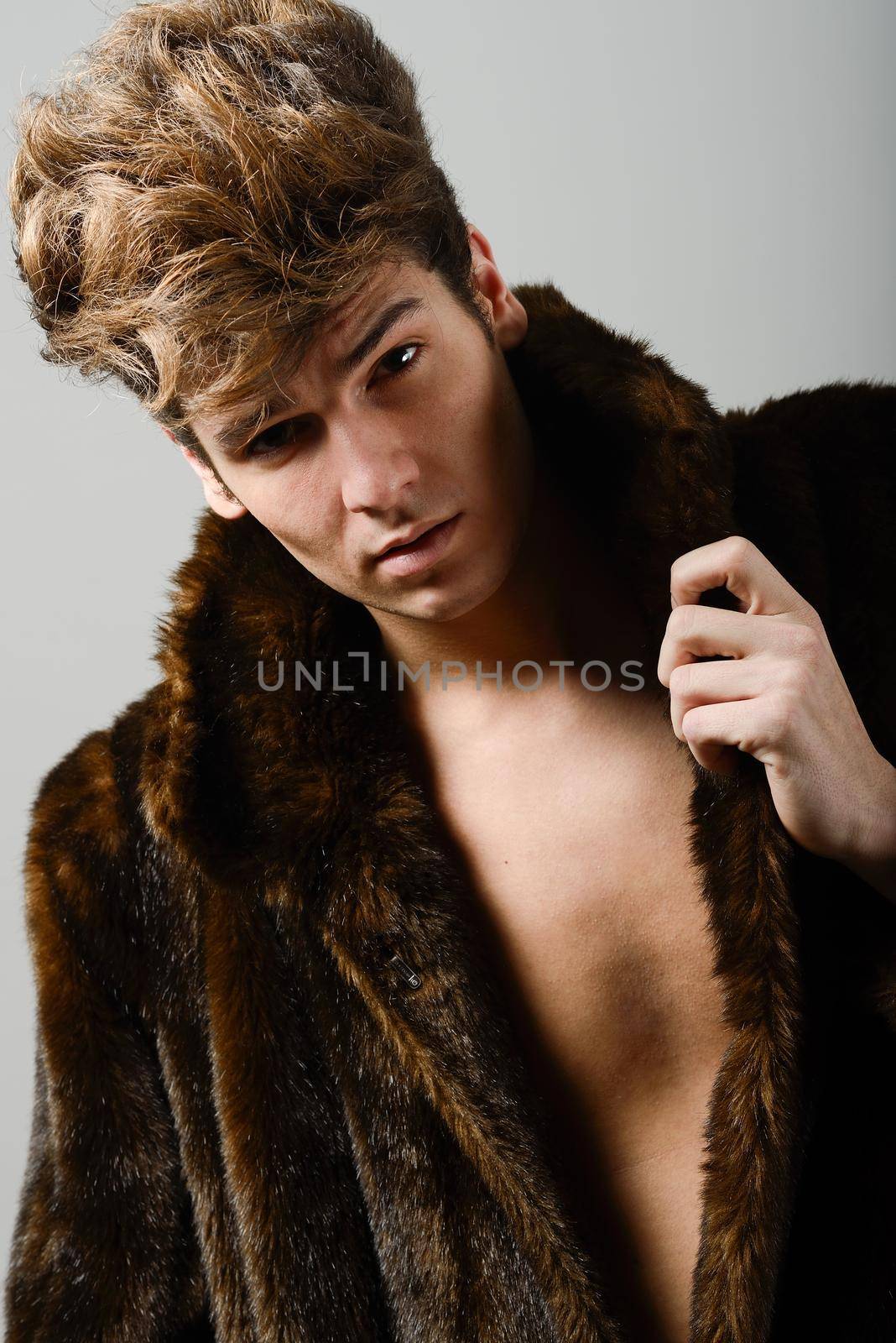 Portrait of a attractive young man wearing fur coat with modern hairstyle