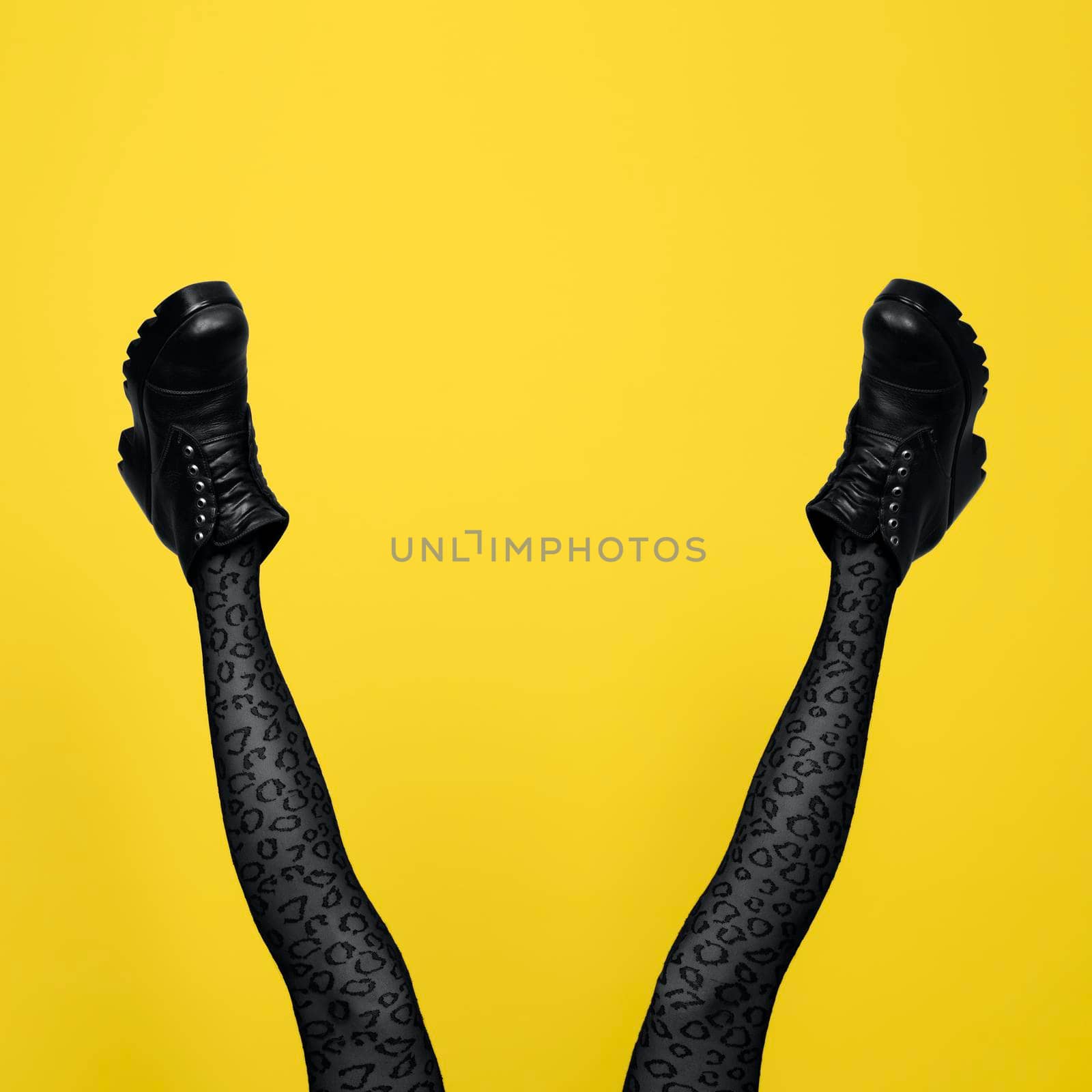 New gray female boots on long slender woman legs in gray tights isolated on yellow background by esvetleishaya