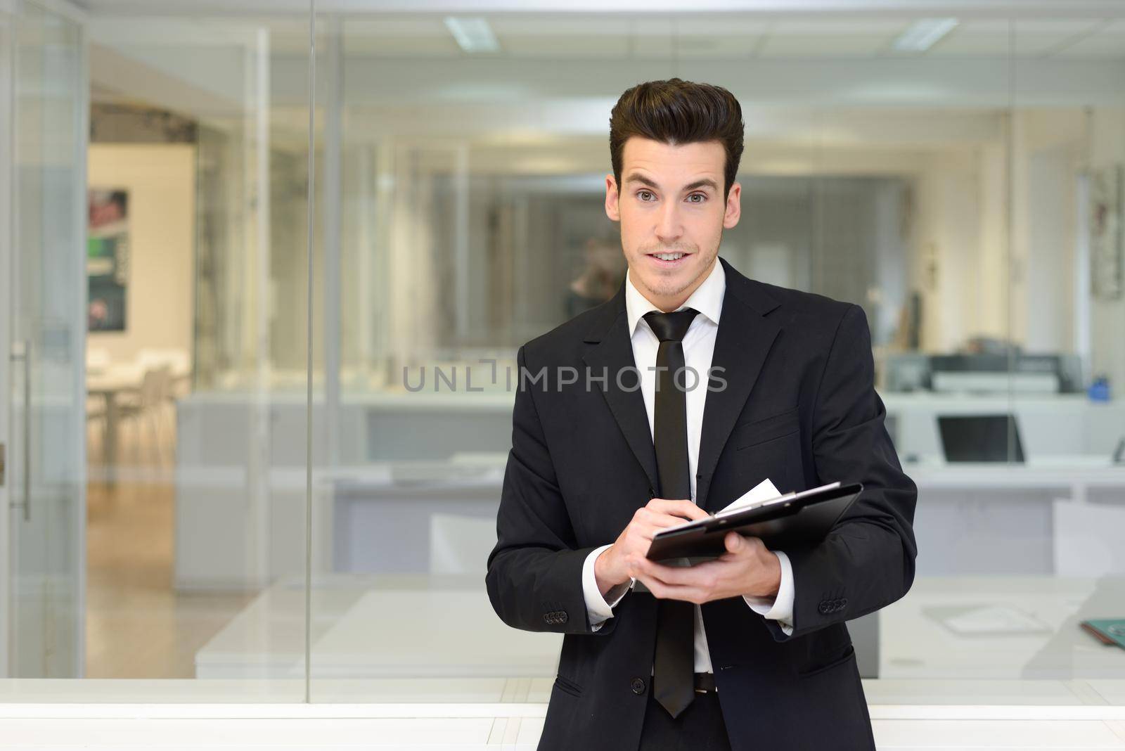 Handsome young businessman in an office by javiindy