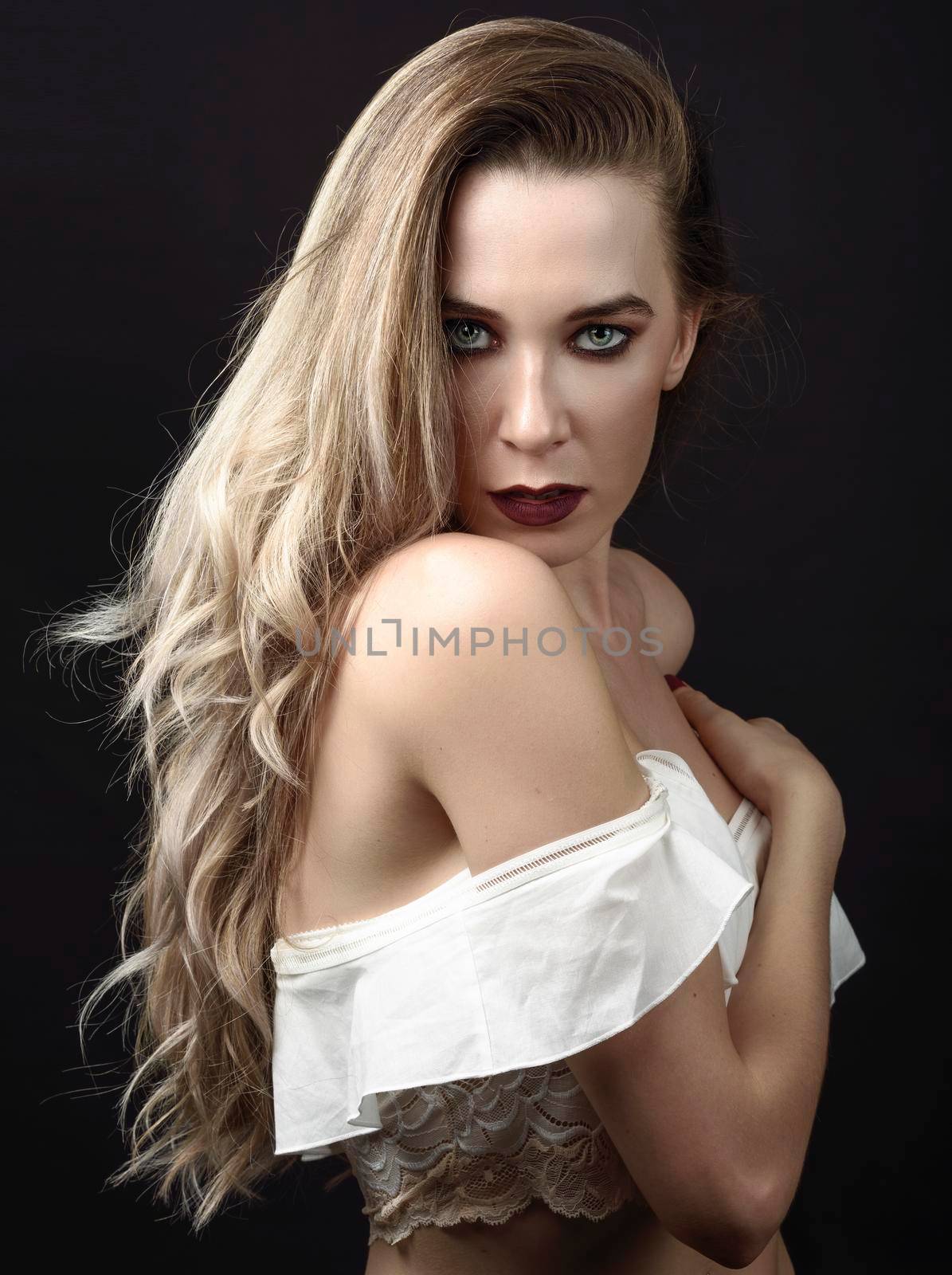 Young woman with long hair and blue eyes against black background with purple make-up. Fashion concept.