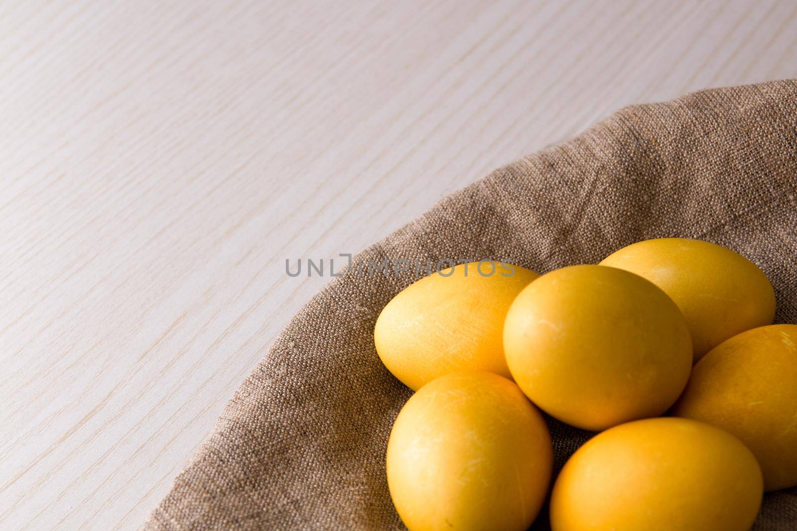 yellow eggs on flax, wooden light background, copy space, top view, easter background, sunlight, religious traditions, conept, close-up