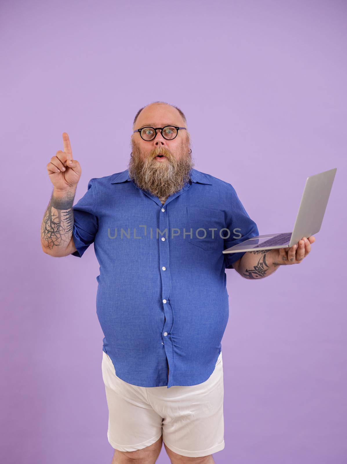 Funny man with overweight got interesting idea holding laptop on purple background by Yaroslav_astakhov