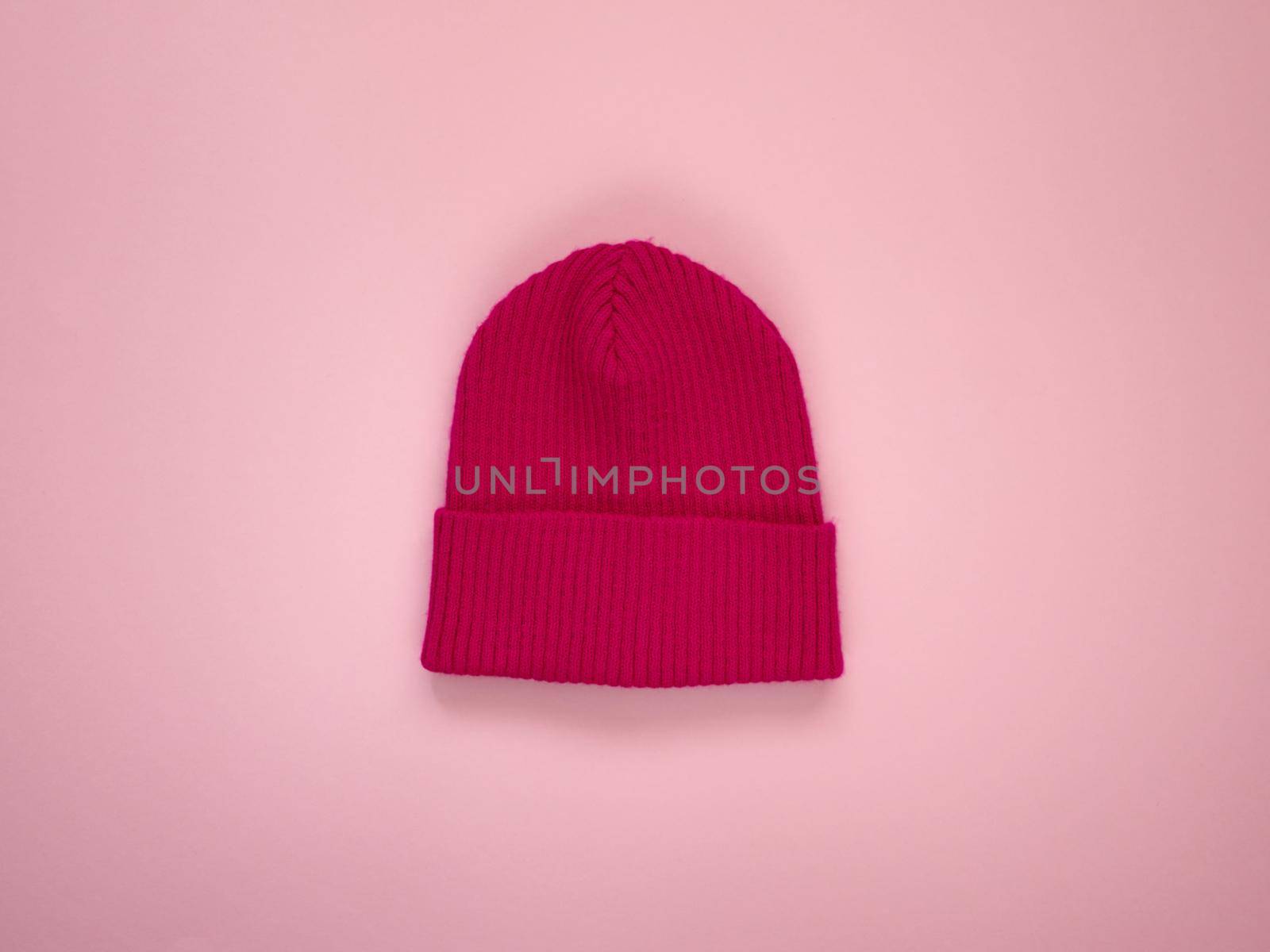 Colorful vivid knitted kids hat. Demi season autumn children's fashion wear. Top view on pink background.