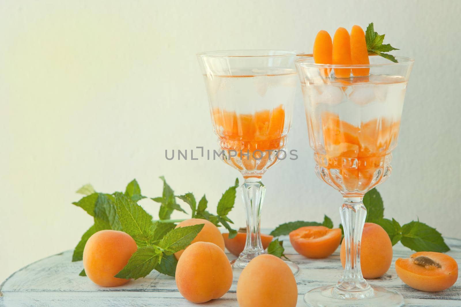 Summer drinks, mint apricot cocktails with ice in glasses. Refreshing summer homemade Alcoholic or non-alcoholic cocktails or Detox infused flavored water by julija