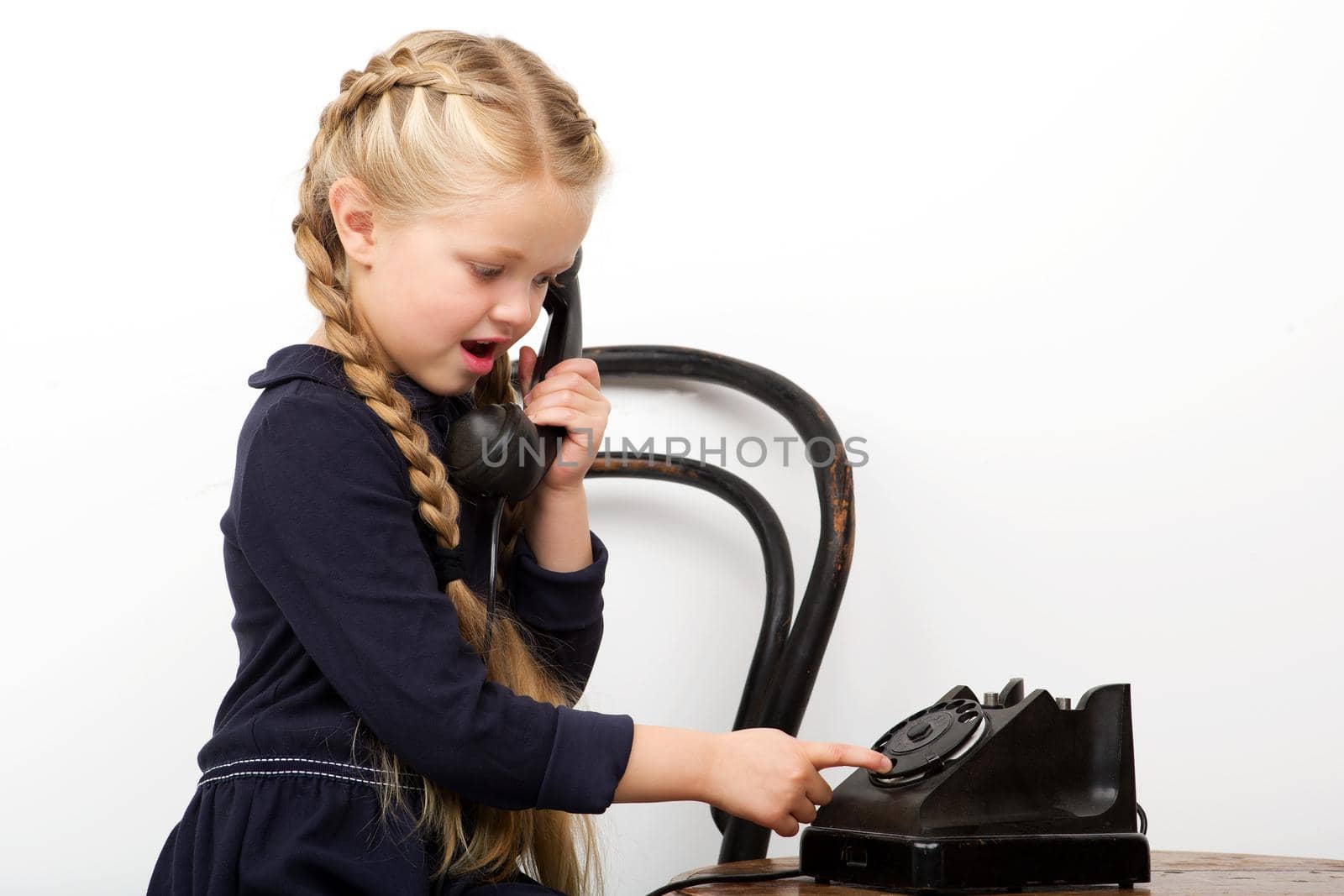 Girl sitting on chair and talking by old phone by kolesnikov_studio