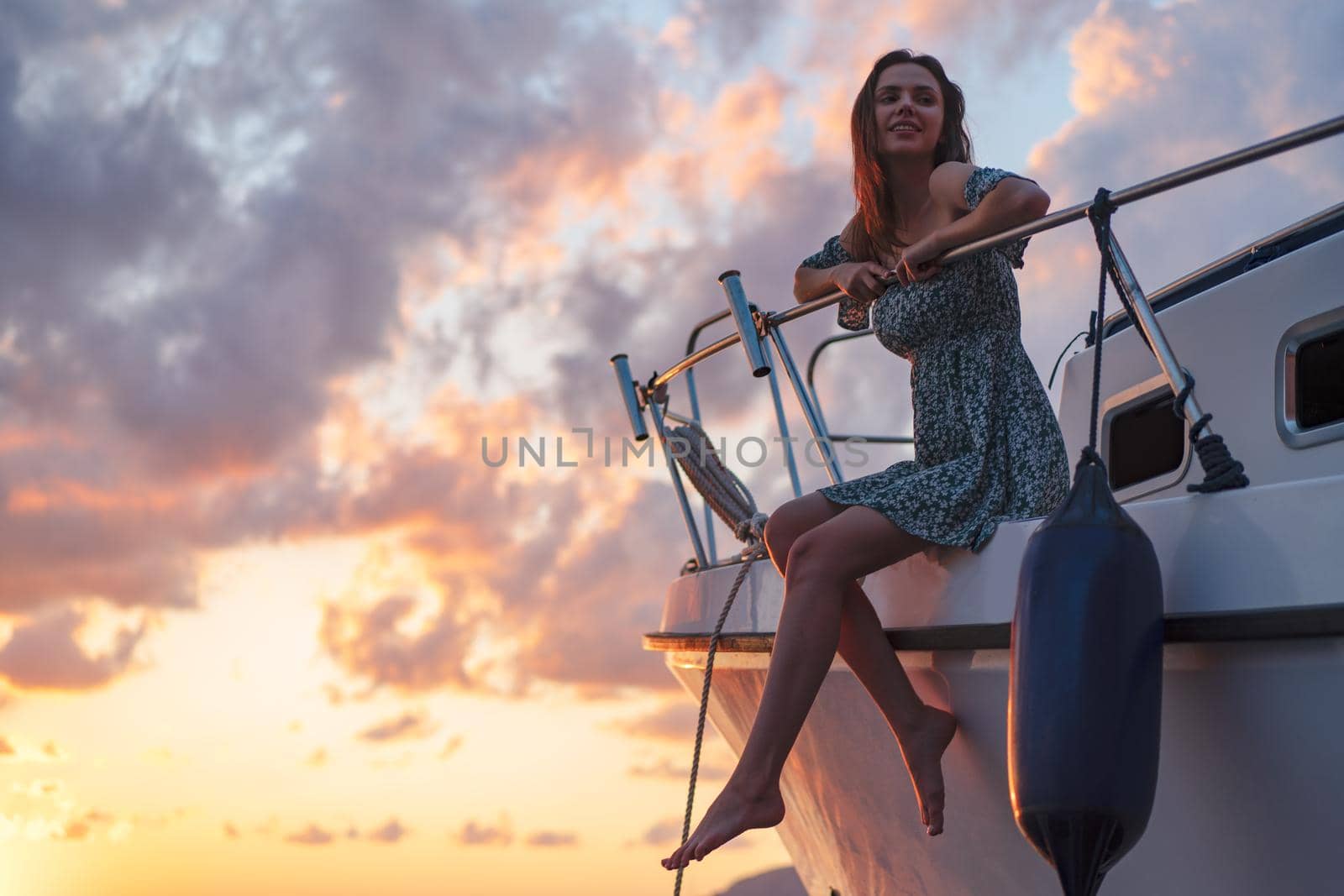 Young attractive woman sitting on the deck of the yacht and enjoying sunset