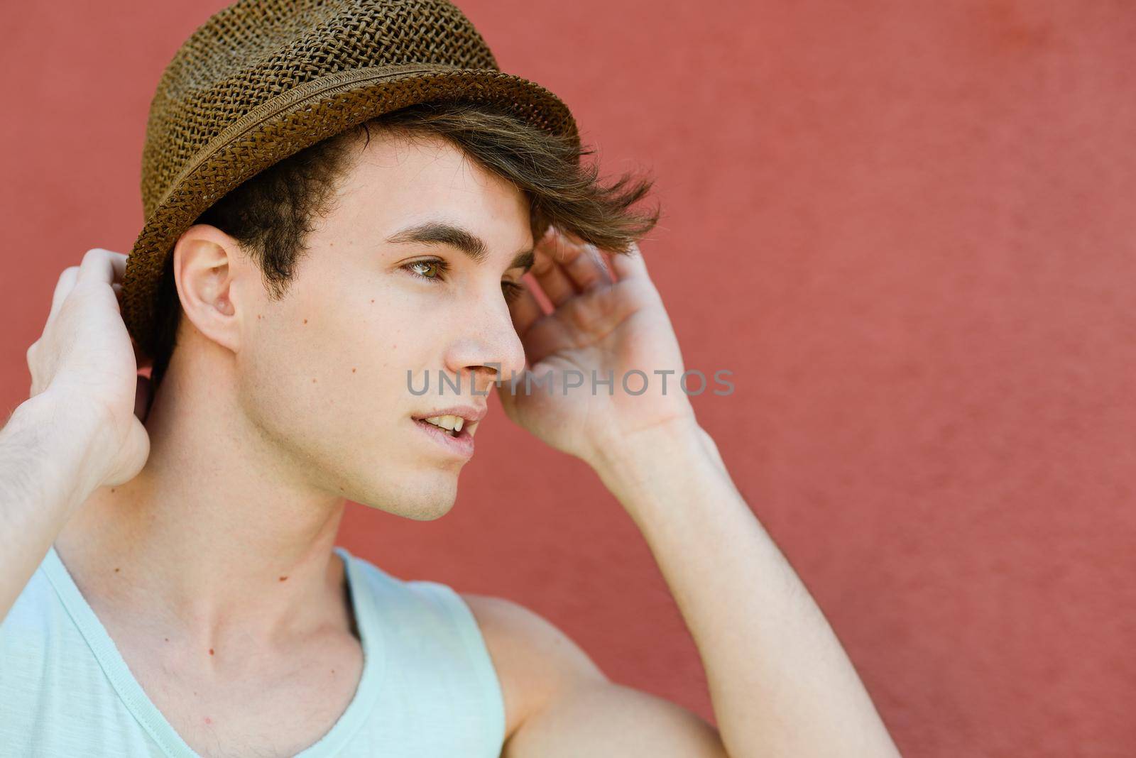 Portrait of attractive young man in urban background wearing a sun hat