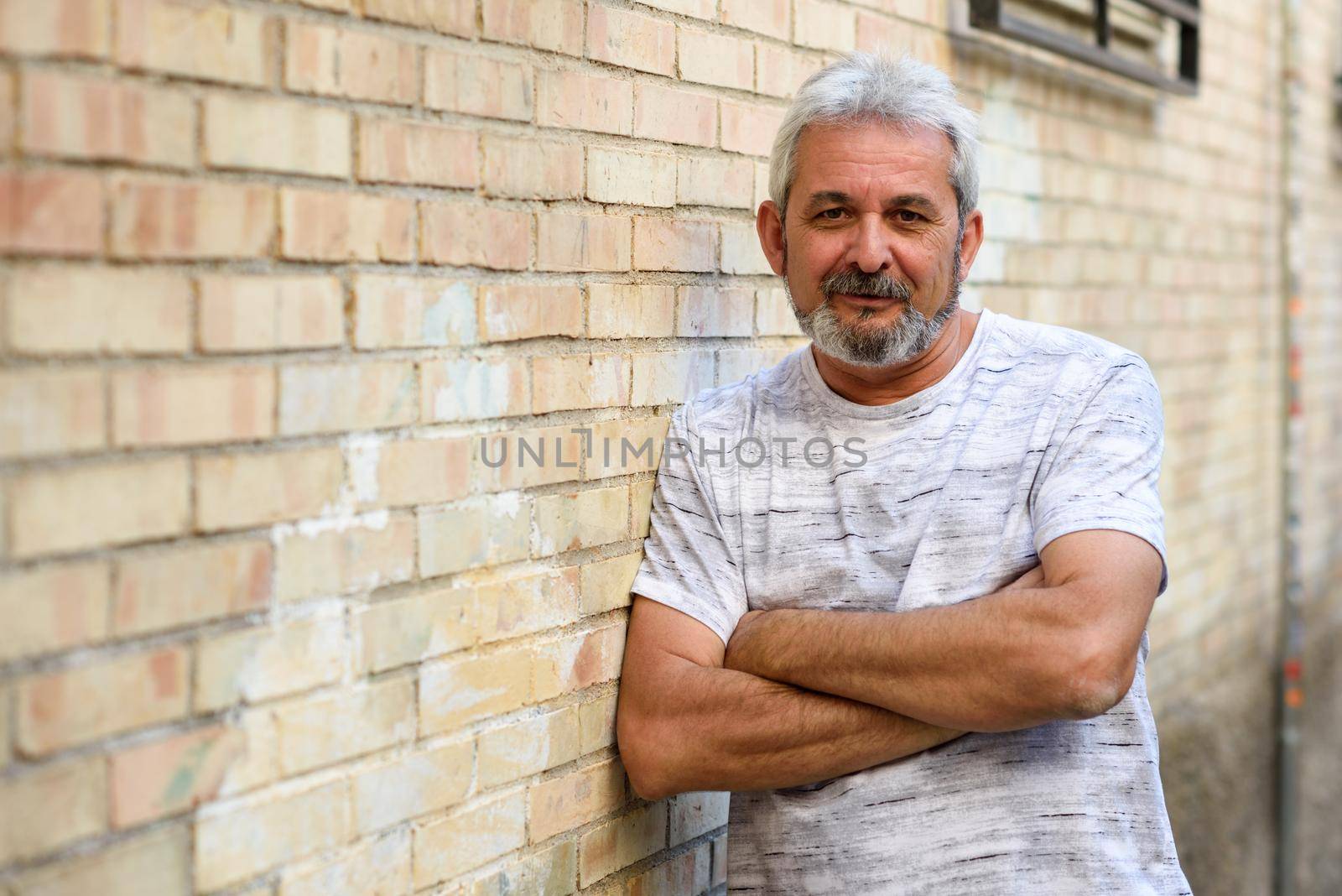 Mature man smiling looking at camera in urban background by javiindy