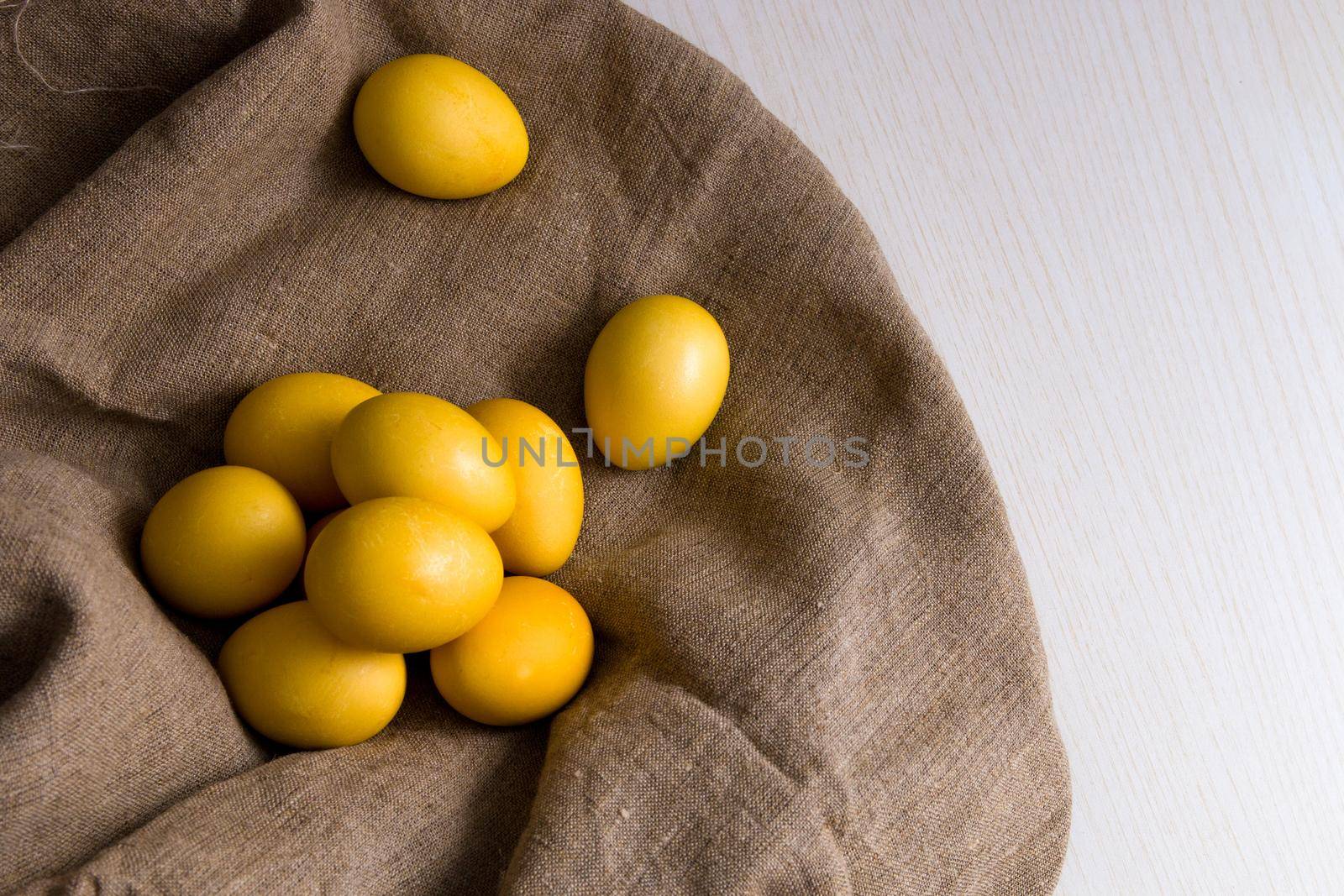 yellow eggs on linen, wooden light background, copy space top view, easter background